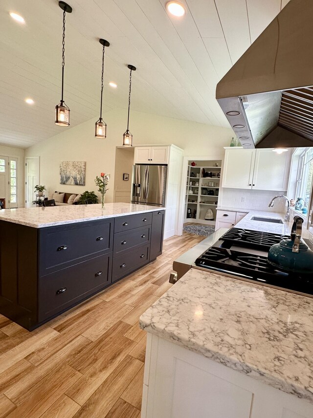 kitchen featuring exhaust hood, stainless steel refrigerator with ice dispenser, white cabinetry, a sink, and a kitchen island