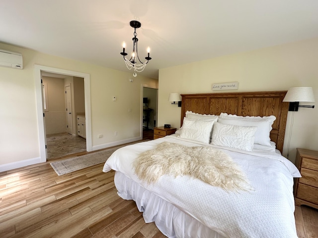 bedroom featuring an AC wall unit, light wood-type flooring, a chandelier, and baseboards