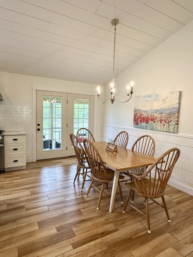 dining space featuring light wood finished floors, a chandelier, and wainscoting
