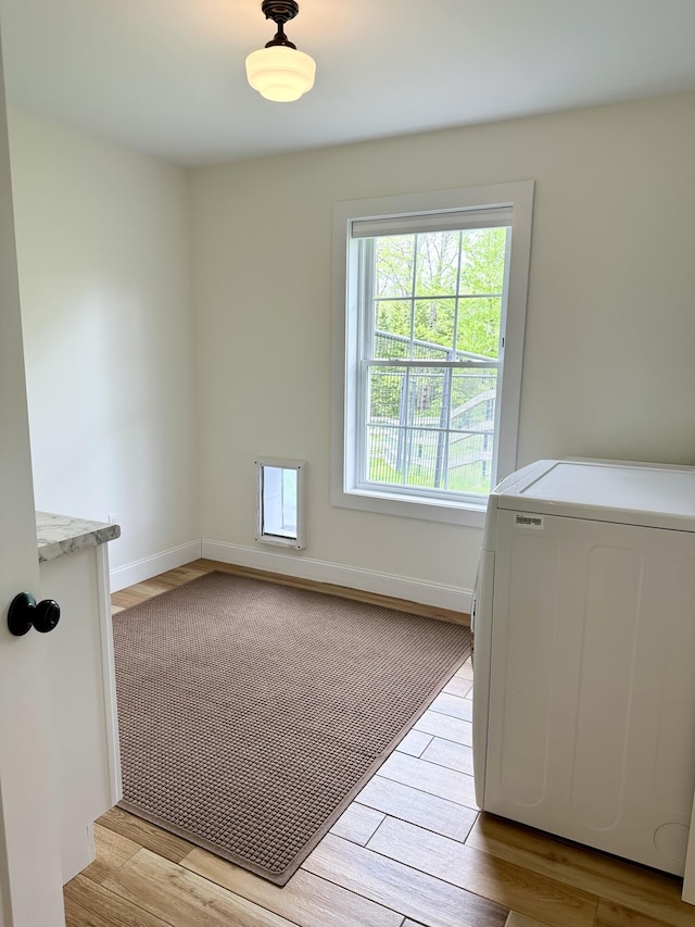 spare room with washer / dryer, light wood-type flooring, and baseboards