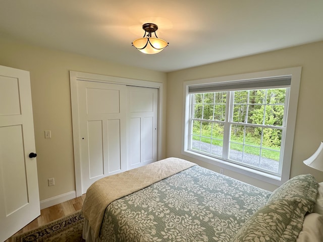 bedroom with wood finished floors, a closet, and baseboards
