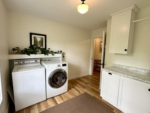 washroom featuring washing machine and dryer, light wood-style flooring, cabinet space, and baseboards