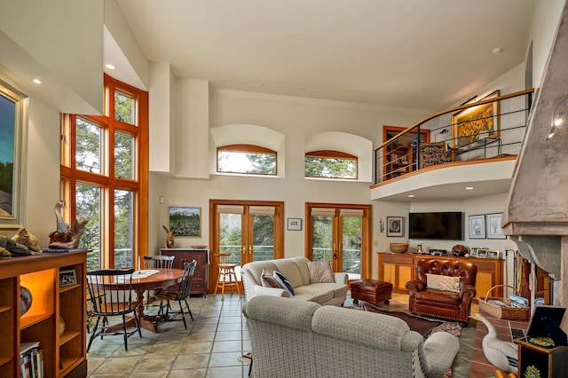 living area featuring a premium fireplace, plenty of natural light, french doors, and a towering ceiling