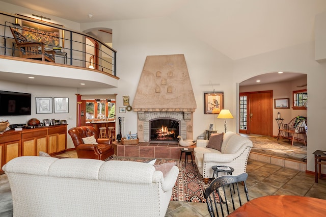 living room with arched walkways, high vaulted ceiling, plenty of natural light, and a fireplace