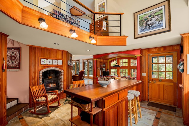 dining area featuring wood walls, a wood stove, and a towering ceiling