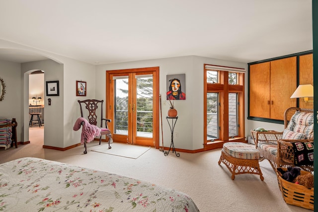 bedroom with baseboards, carpet flooring, arched walkways, and access to exterior