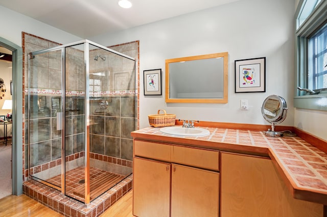 full bath featuring vanity, a shower stall, and wood finished floors