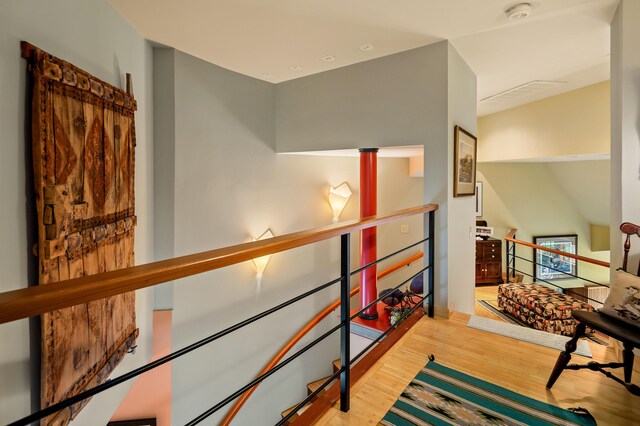 hall featuring an upstairs landing and wood finished floors