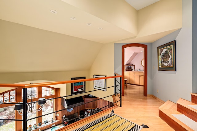 hallway with recessed lighting, lofted ceiling, light wood finished floors, and an upstairs landing