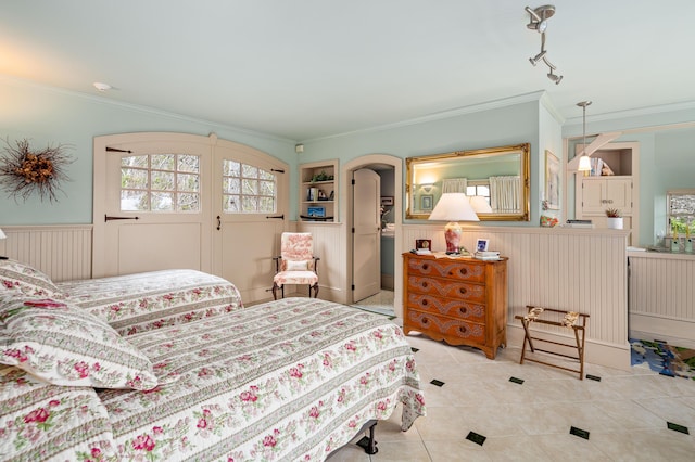 bedroom with ornamental molding, wainscoting, arched walkways, and tile patterned floors