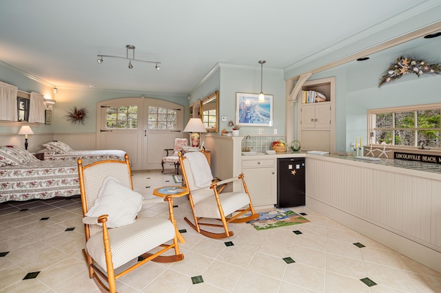 bedroom with crown molding, light tile patterned floors, a wainscoted wall, and a sink
