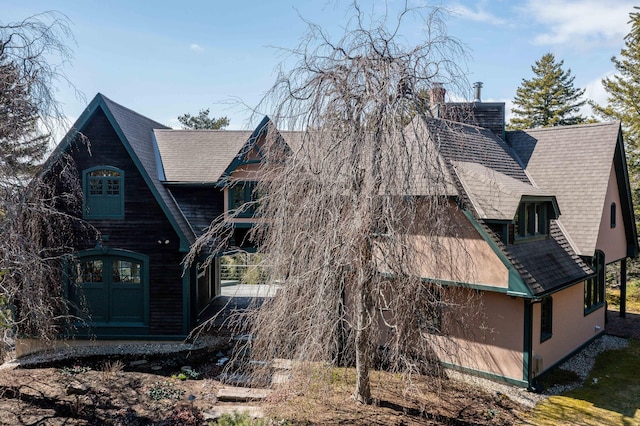 view of side of home featuring roof with shingles and a chimney