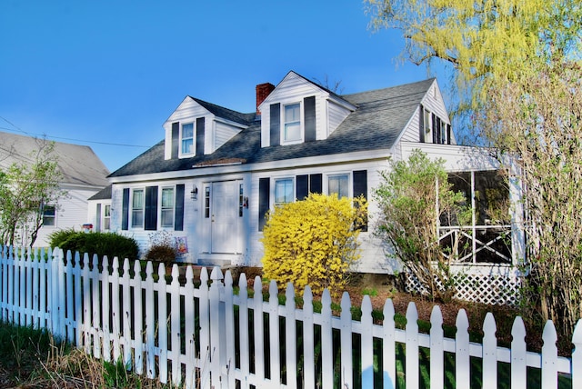 new england style home with a fenced front yard and a chimney