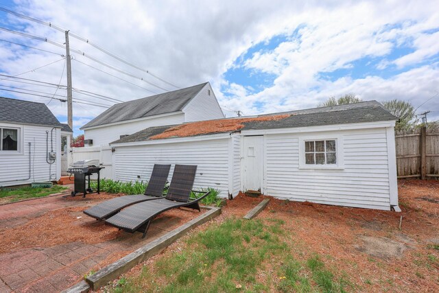 back of house featuring fence and an outbuilding