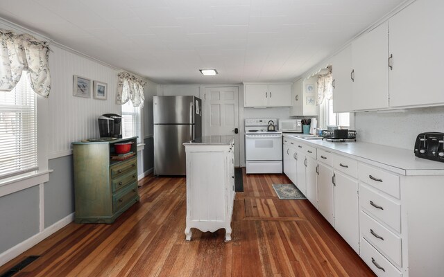 kitchen with white appliances, a center island, dark wood-style floors, a sink, and white cabinets