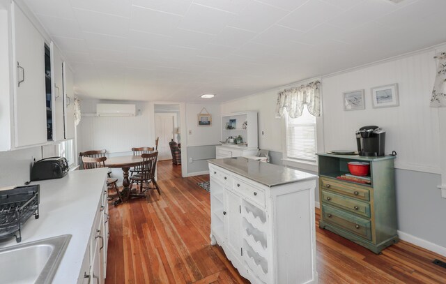 kitchen featuring white cabinetry, a wall mounted AC, wood finished floors, and light countertops