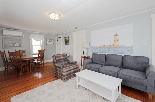 living area featuring a wall mounted AC, wood finished floors, and baseboards