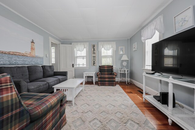 living room with healthy amount of natural light, wood finished floors, crown molding, and baseboards