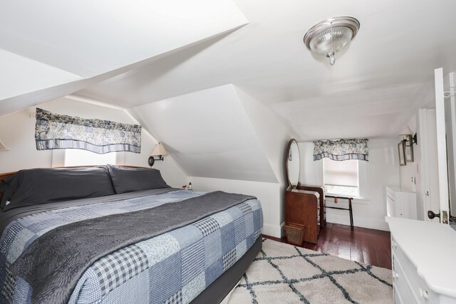 bedroom with wood finished floors, vaulted ceiling, and baseboards