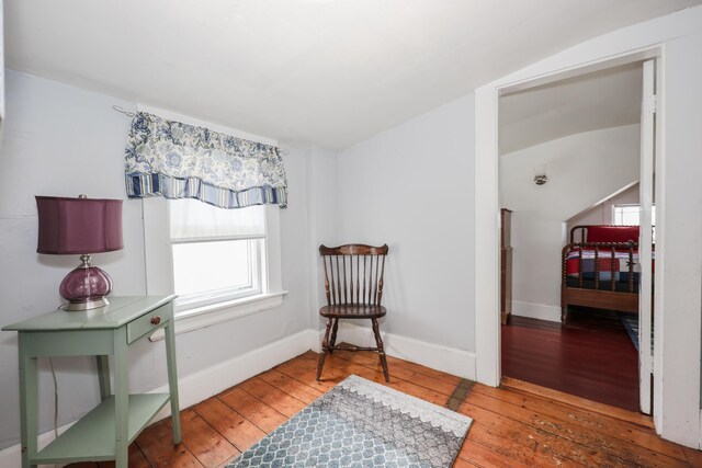 living area featuring hardwood / wood-style floors, baseboards, and lofted ceiling