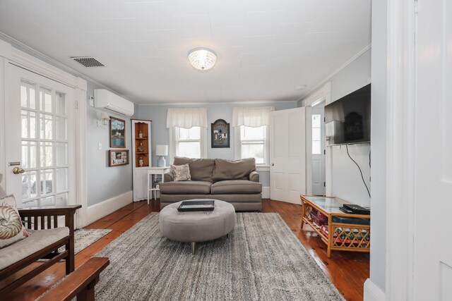 living area with a wall mounted air conditioner, ornamental molding, dark wood-type flooring, and baseboards