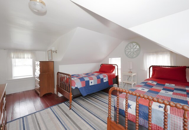 bedroom with hardwood / wood-style floors, multiple windows, and vaulted ceiling