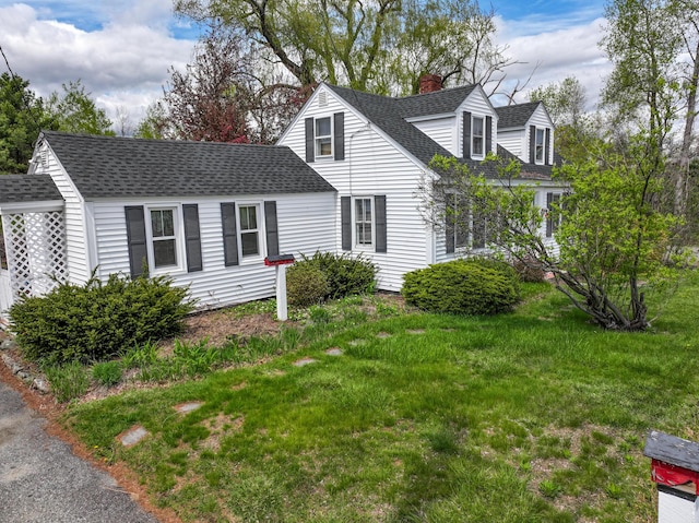 view of front of house with a chimney, roof with shingles, and a front yard