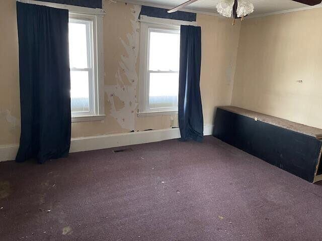 carpeted spare room with crown molding and baseboards