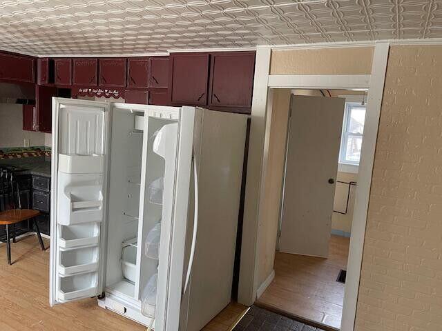 room details featuring an ornate ceiling, freestanding refrigerator, and wood finished floors