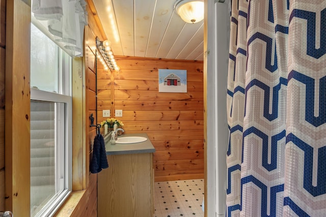 full bathroom featuring wooden walls, tile patterned floors, curtained shower, and vanity