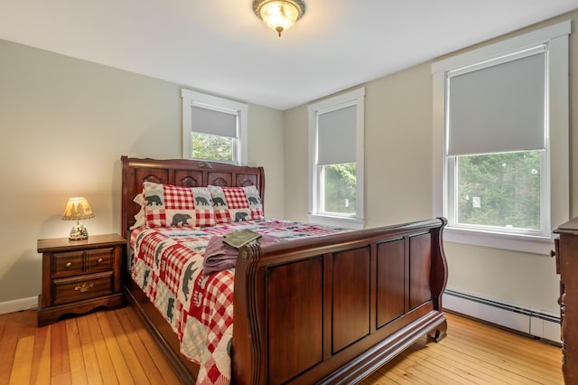bedroom with a baseboard heating unit and light wood-type flooring