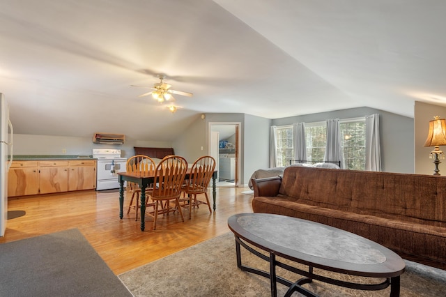 living room with a ceiling fan, vaulted ceiling, and light wood-style floors
