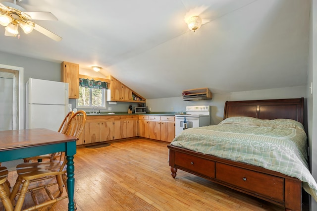 bedroom with freestanding refrigerator, a sink, light wood finished floors, and lofted ceiling