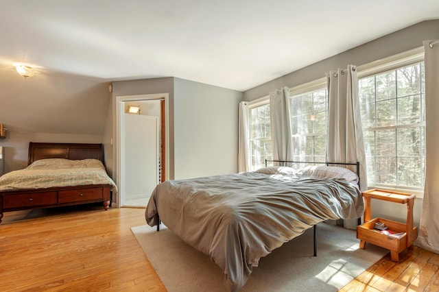 bedroom with light wood-type flooring and vaulted ceiling