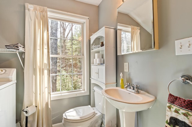 half bath featuring washer / clothes dryer, a wealth of natural light, and toilet
