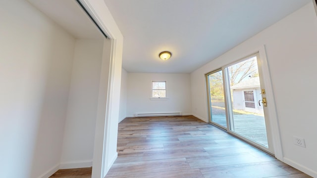 unfurnished room with baseboards, a baseboard radiator, and light wood-type flooring