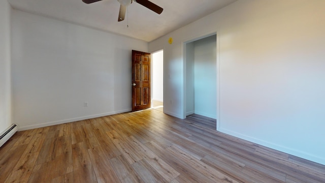 spare room with light wood-style floors, baseboards, ceiling fan, and a baseboard heating unit