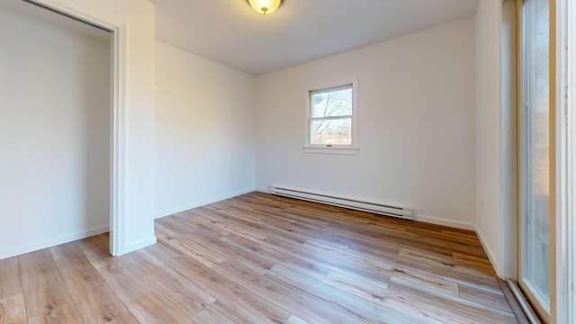 empty room with baseboards, a baseboard radiator, and light wood-style flooring