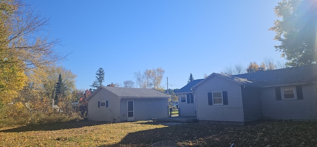 back of property with a yard and an outdoor structure