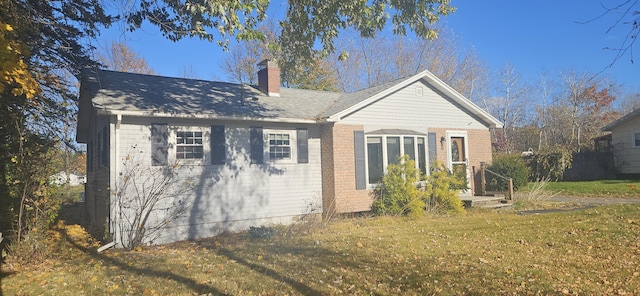 rear view of property featuring a yard, brick siding, and a chimney