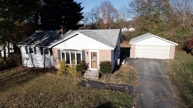 view of front of home featuring brick siding, a chimney, an outdoor structure, and a garage