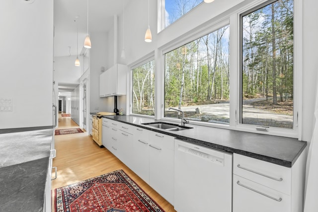 27 Carter Dr, West Bath, ME 04530 - kitchen featuring dark countertops, dishwasher, a sink, light wood-style floors, and white cabinets