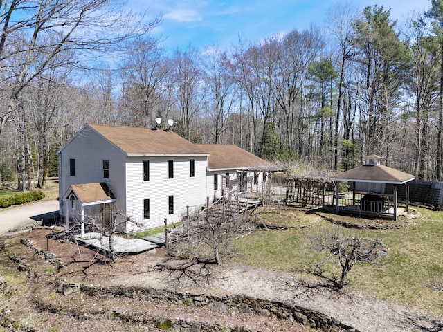 view of side of property with roof with shingles and a gazebo