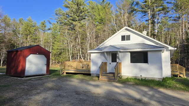 341 E Andover Rd, Andover, ME 04226 - view of front of property with metal roof, a storage shed, a deck, an outbuilding, and a view of trees