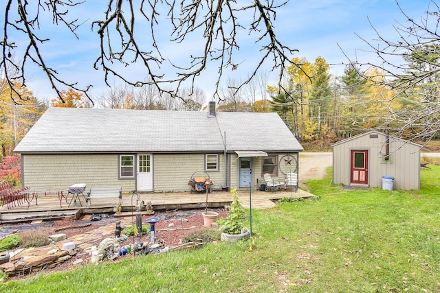 405 Pond Rd, Sidney, ME 04330 - rear view of property featuring an outdoor structure, a wooden deck, a shed, a shingled roof, and a lawn