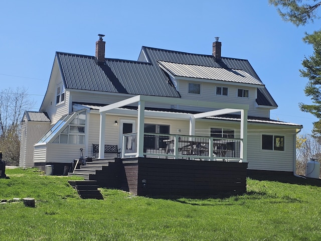 rear view of property featuring a lawn, a chimney, and metal roof