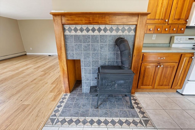 222 Ward Rd, Augusta, ME 04330 - detailed view of white appliances, a wood stove, baseboards, and a baseboard radiator