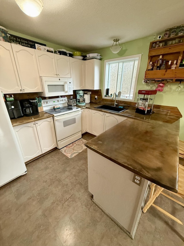 12 Grace Snow Dr, Glenburn, ME 04401 - kitchen with white appliances, a sink, dark countertops, white cabinetry, and a peninsula
