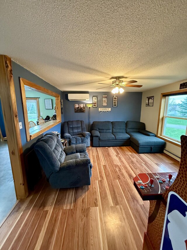 12 Grace Snow Dr, Glenburn, ME 04401 - living room with a textured ceiling, wood finished floors, a wall mounted air conditioner, a ceiling fan, and baseboard heating