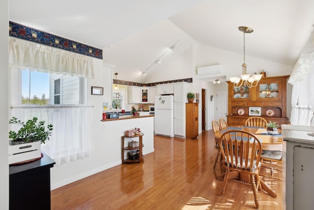 61 Pond Rd, Albion, ME 04910 - dining room featuring high vaulted ceiling, baseboards, an AC wall unit, a chandelier, and light wood-style floors